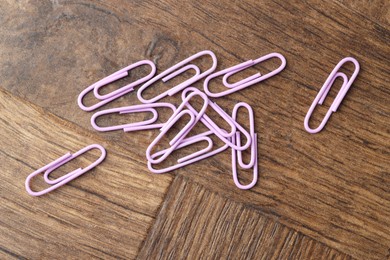 Many violet paper clips on wooden table, flat lay