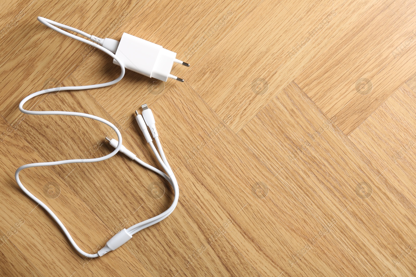 Photo of USB power adapter with triple charge cable on wooden table, top view. Space for text