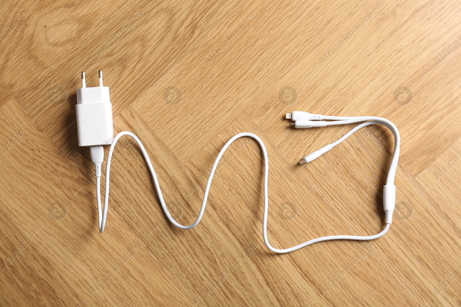 Photo of USB power adapter with triple charge cable on wooden table, top view