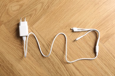 Photo of USB power adapter with triple charge cable on wooden table, top view