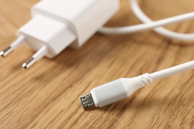 Photo of USB power adapter with charge cable on wooden table, closeup