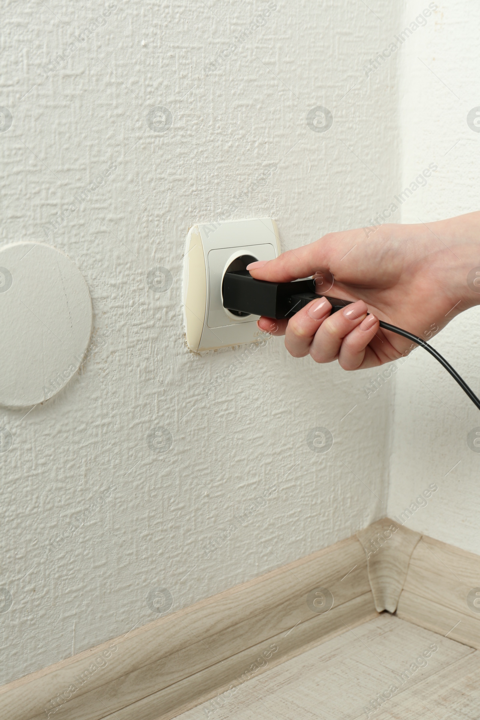 Photo of Woman plugging USB power adapter with charge cable into electrical socket indoors, closeup