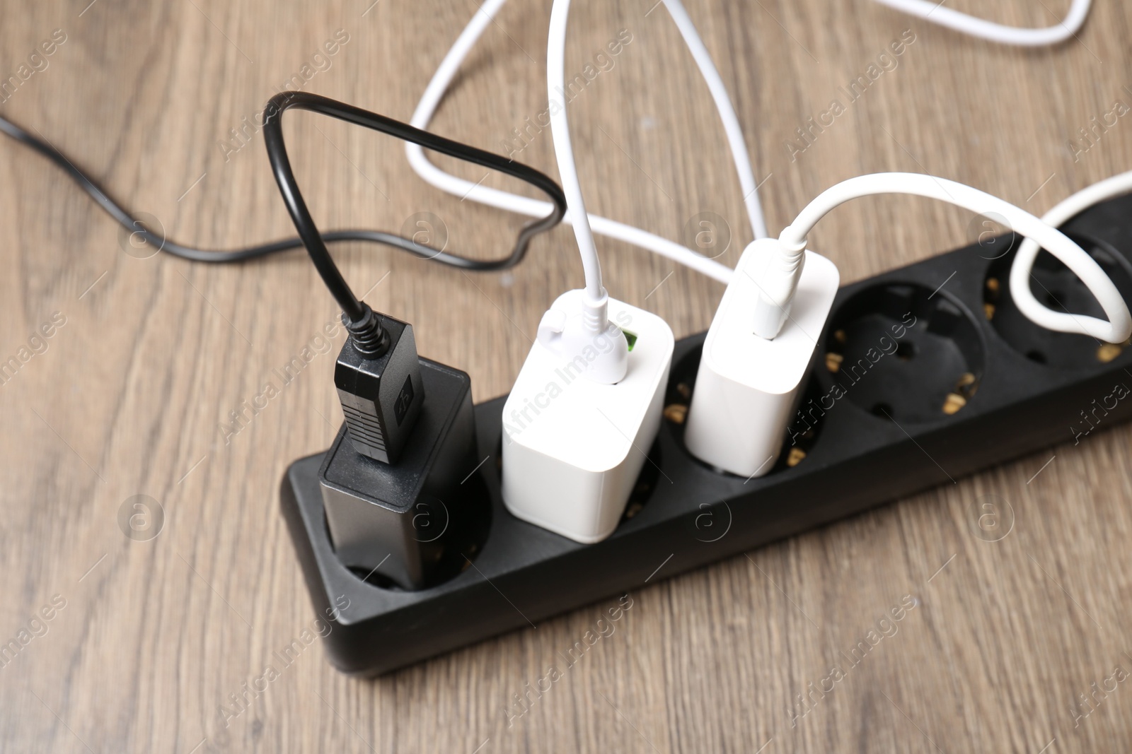 Photo of USB adapters with charge cables in power strip on floor, closeup