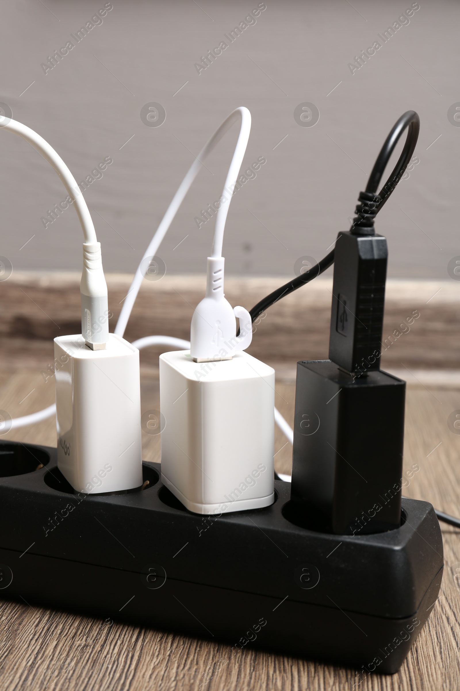 Photo of USB adapters with charge cables in power strip on floor indoors, closeup