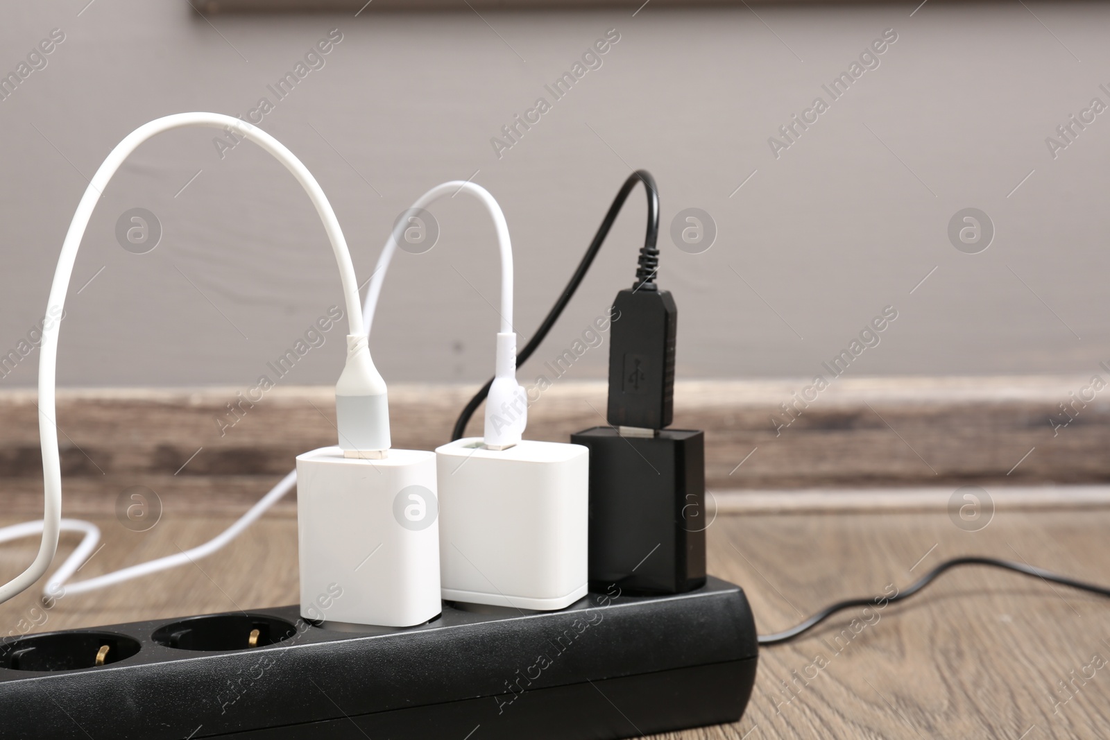 Photo of USB adapters with charge cables in power strip on floor indoors, closeup