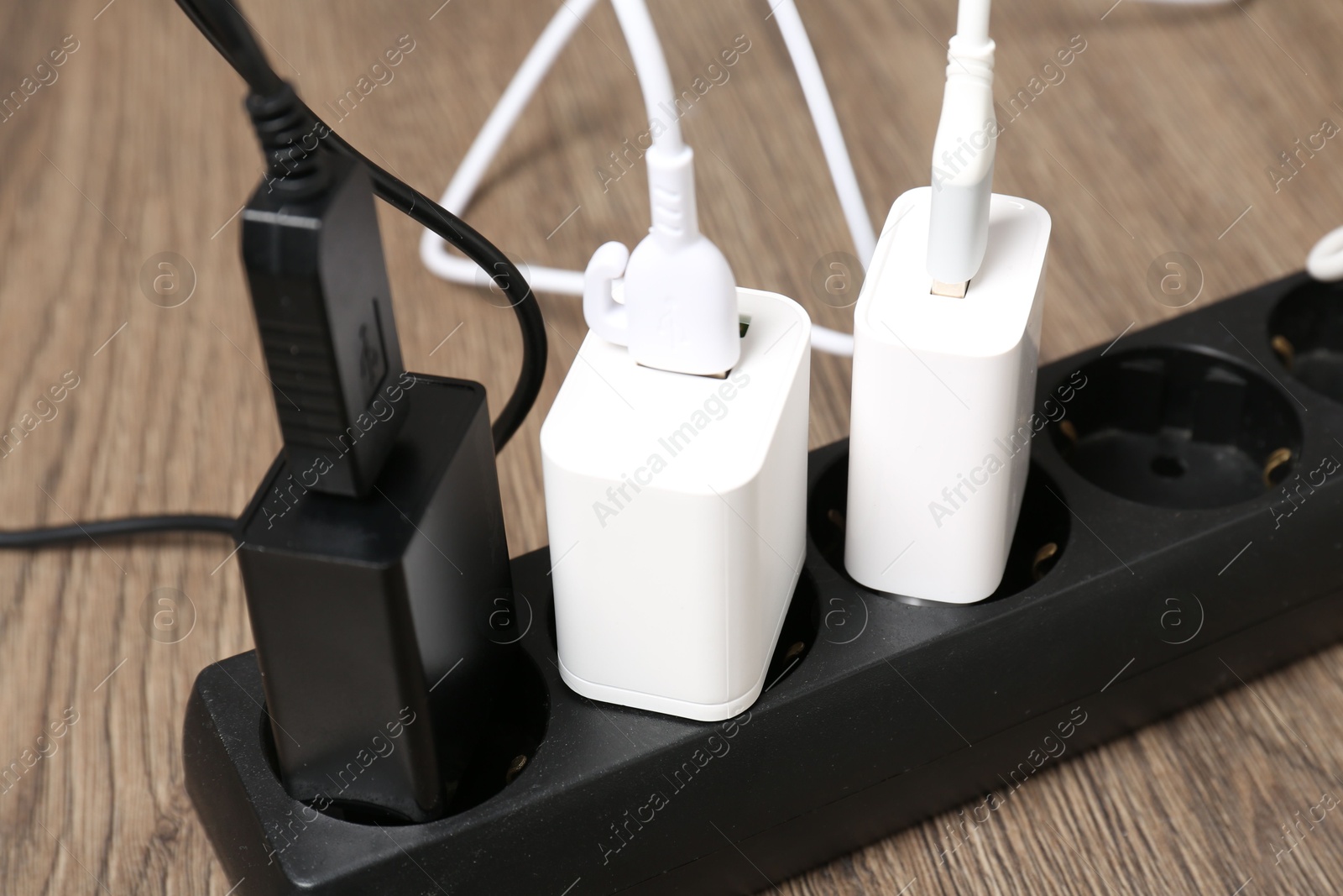 Photo of USB adapters with charge cables in power strip on floor, closeup