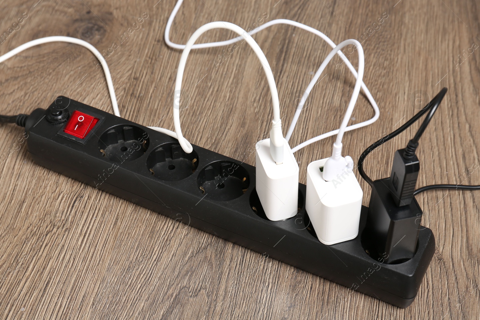 Photo of USB adapters with charge cables in power strip on floor, closeup