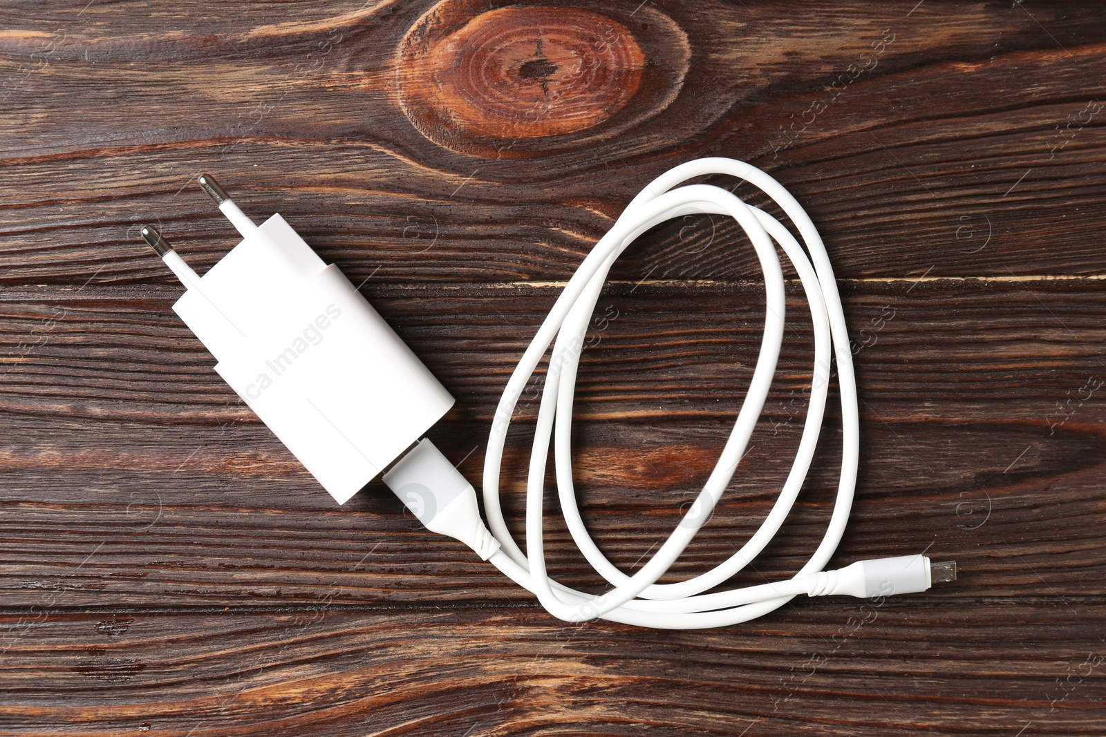 Photo of USB power adapter with charge cable on wooden table, top view