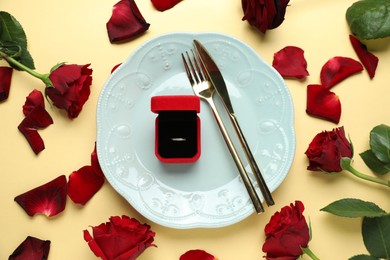 Photo of Beautiful setting for romantic dinner, engagement ring and roses on beige background, flat lay