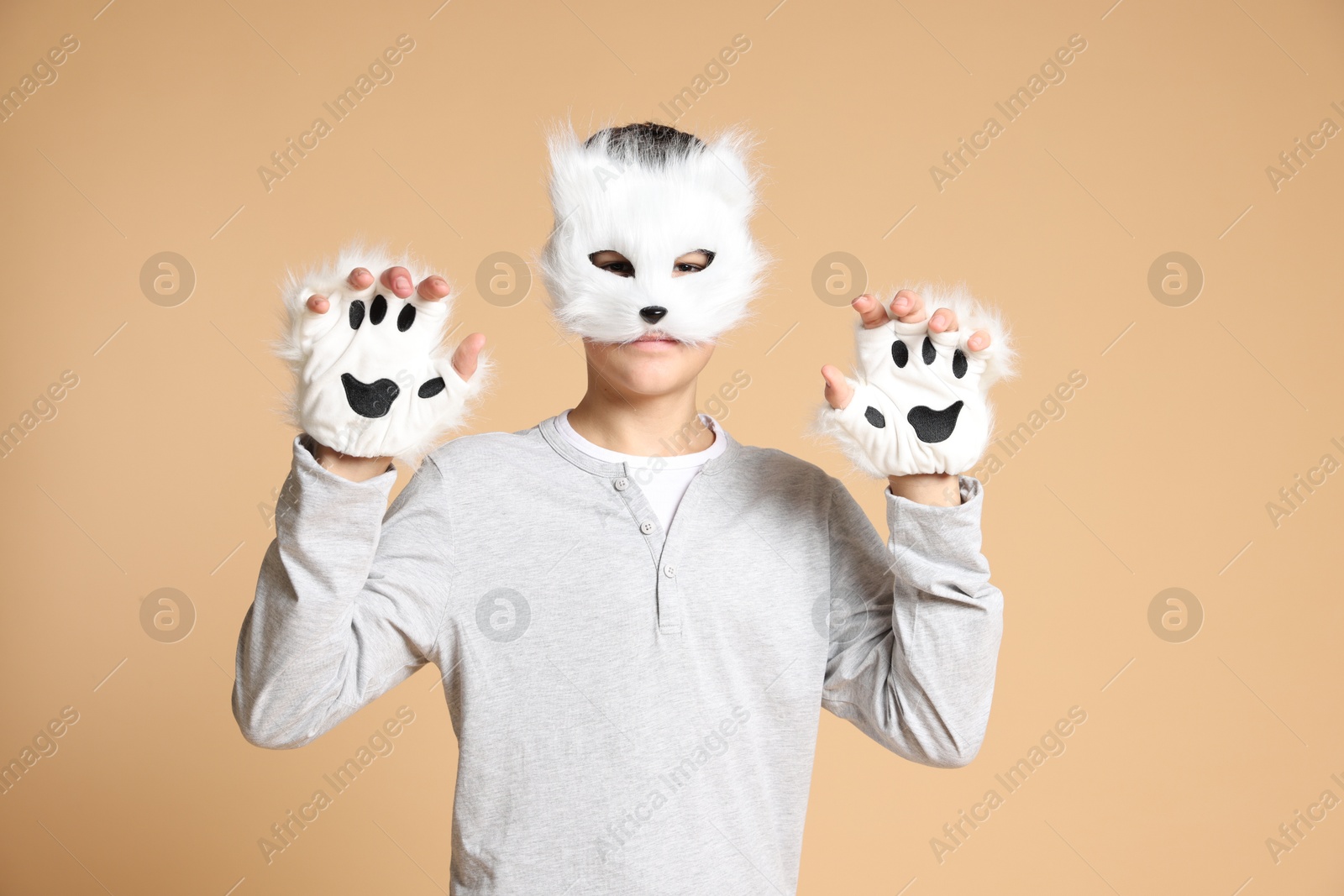 Photo of Quadrobics. Boy wearing cat mask and gloves on beige background