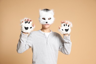 Quadrobics. Boy wearing cat mask and gloves on beige background