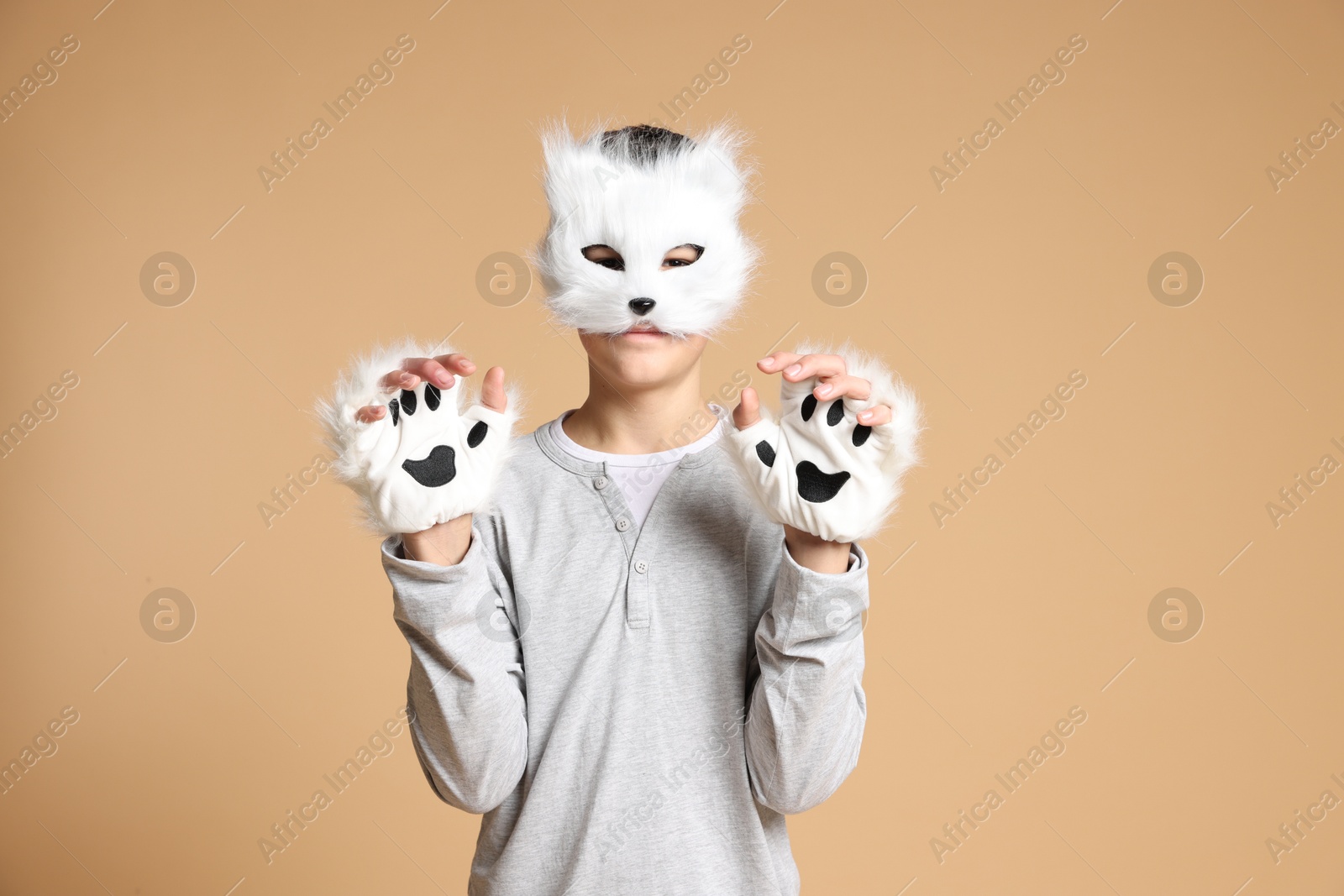 Photo of Quadrobics. Boy wearing cat mask and gloves on beige background