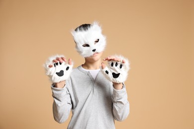 Quadrobics. Boy wearing cat mask and gloves on beige background