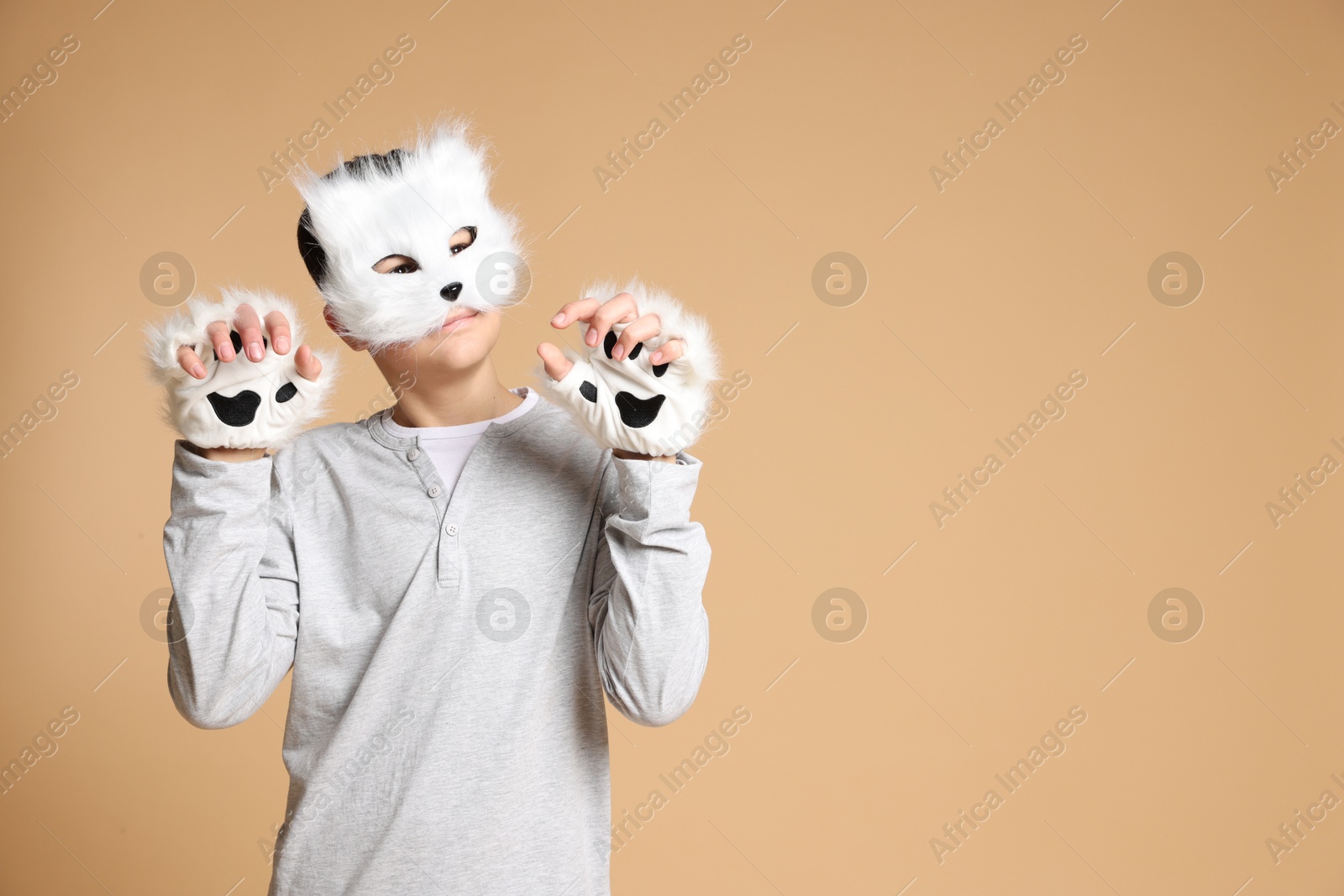 Photo of Quadrobics. Boy wearing cat mask and gloves on beige background, space for text