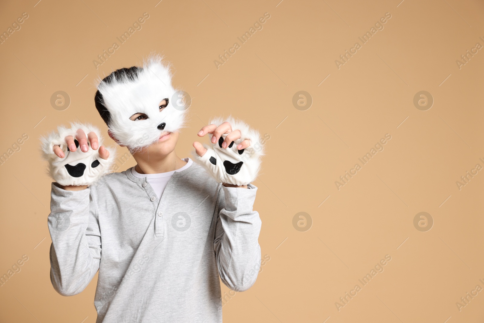 Photo of Quadrobics. Boy wearing cat mask and gloves on beige background, space for text