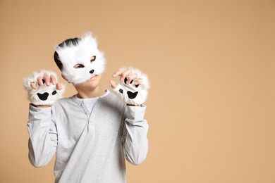 Quadrobics. Boy wearing cat mask and gloves on beige background, space for text