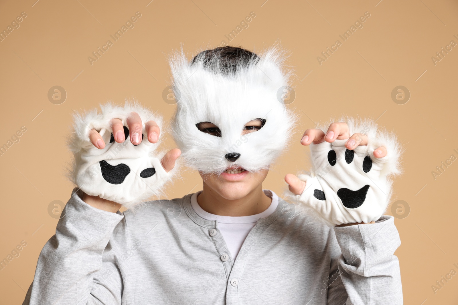 Photo of Quadrobics. Boy wearing cat mask and gloves on beige background