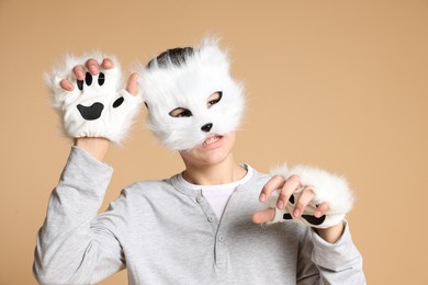 Quadrobics. Boy wearing cat mask and gloves on beige background