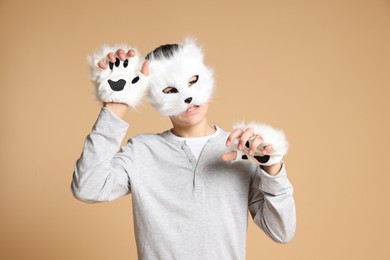 Quadrobics. Boy wearing cat mask and gloves on beige background