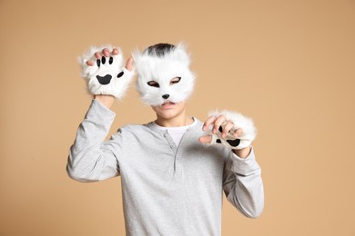 Quadrobics. Boy wearing cat mask and gloves on beige background