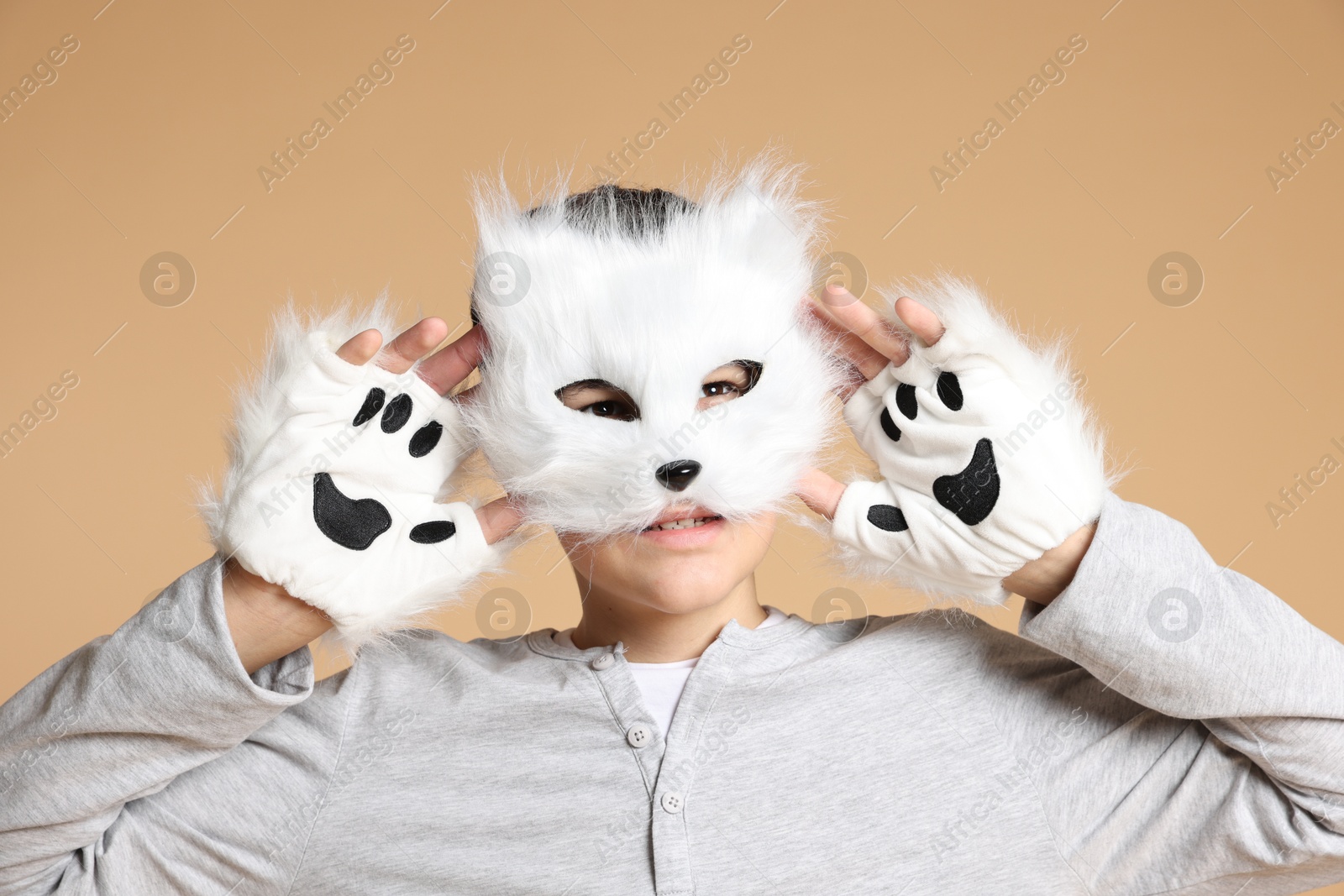 Photo of Quadrobics. Boy wearing cat mask and gloves on beige background