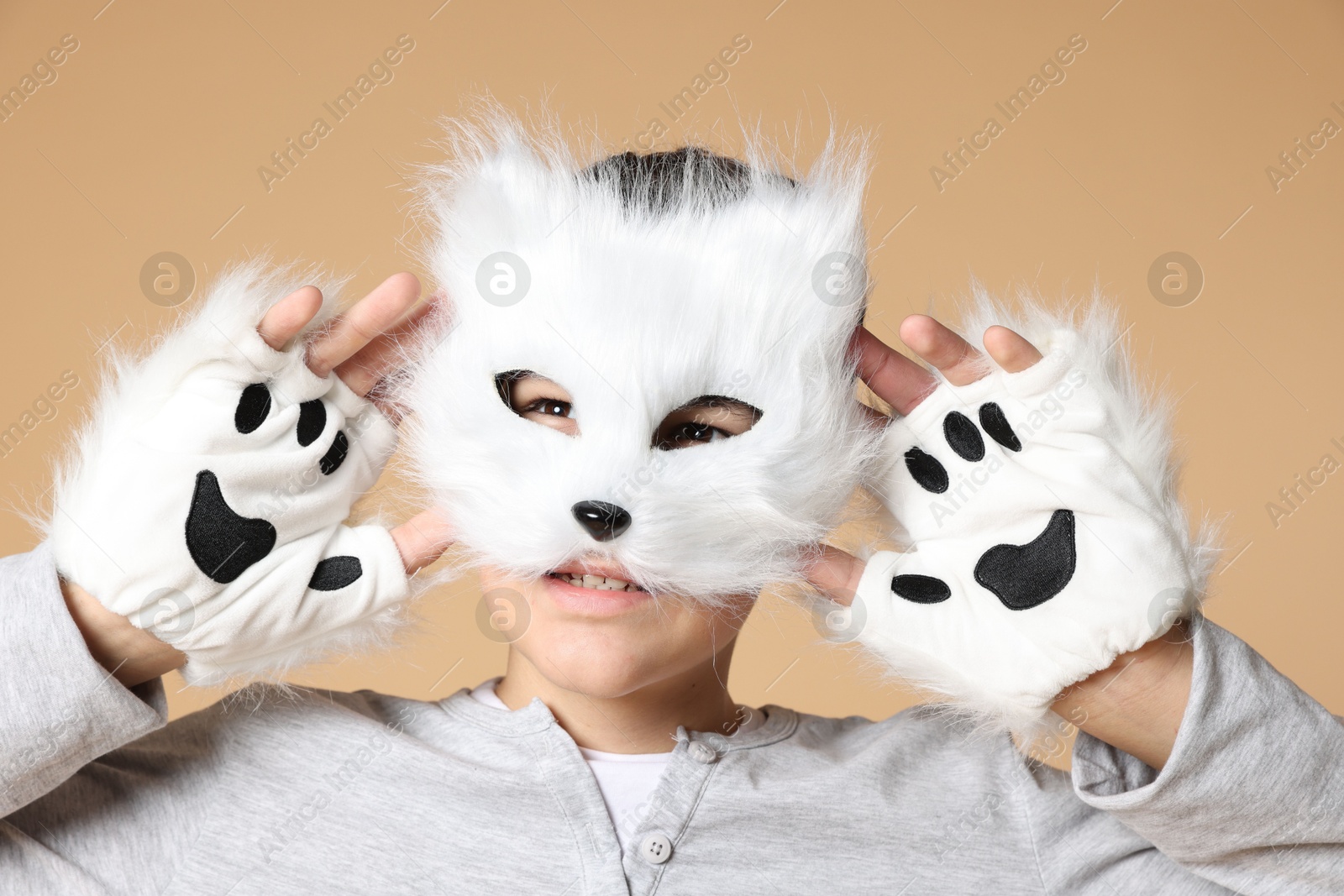 Photo of Quadrobics. Boy wearing cat mask and gloves on beige background