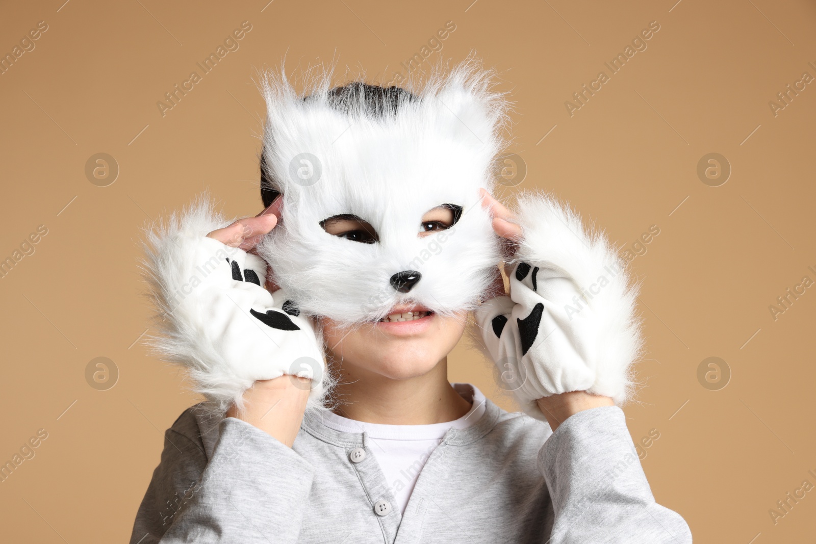 Photo of Quadrobics. Boy wearing cat mask and gloves on beige background