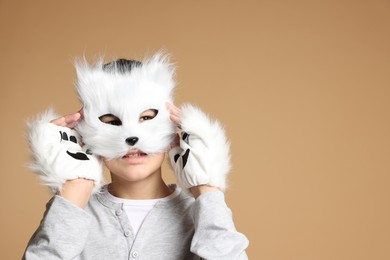 Photo of Quadrobics. Boy wearing cat mask and gloves on beige background, space for text