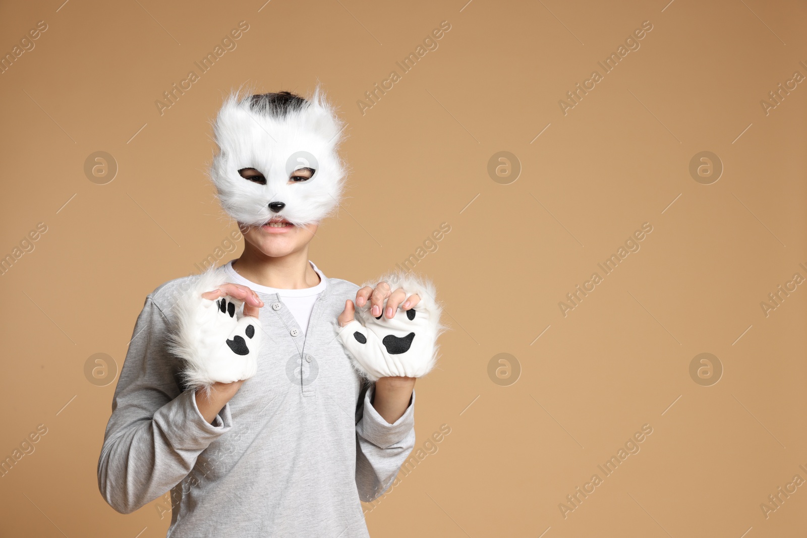 Photo of Quadrobics. Boy wearing cat mask and gloves on beige background, space for text