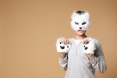 Photo of Quadrobics. Boy wearing cat mask and gloves on beige background, space for text