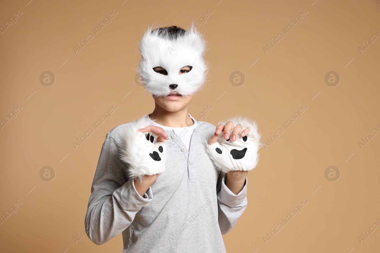 Photo of Quadrobics. Boy wearing cat mask and gloves on beige background