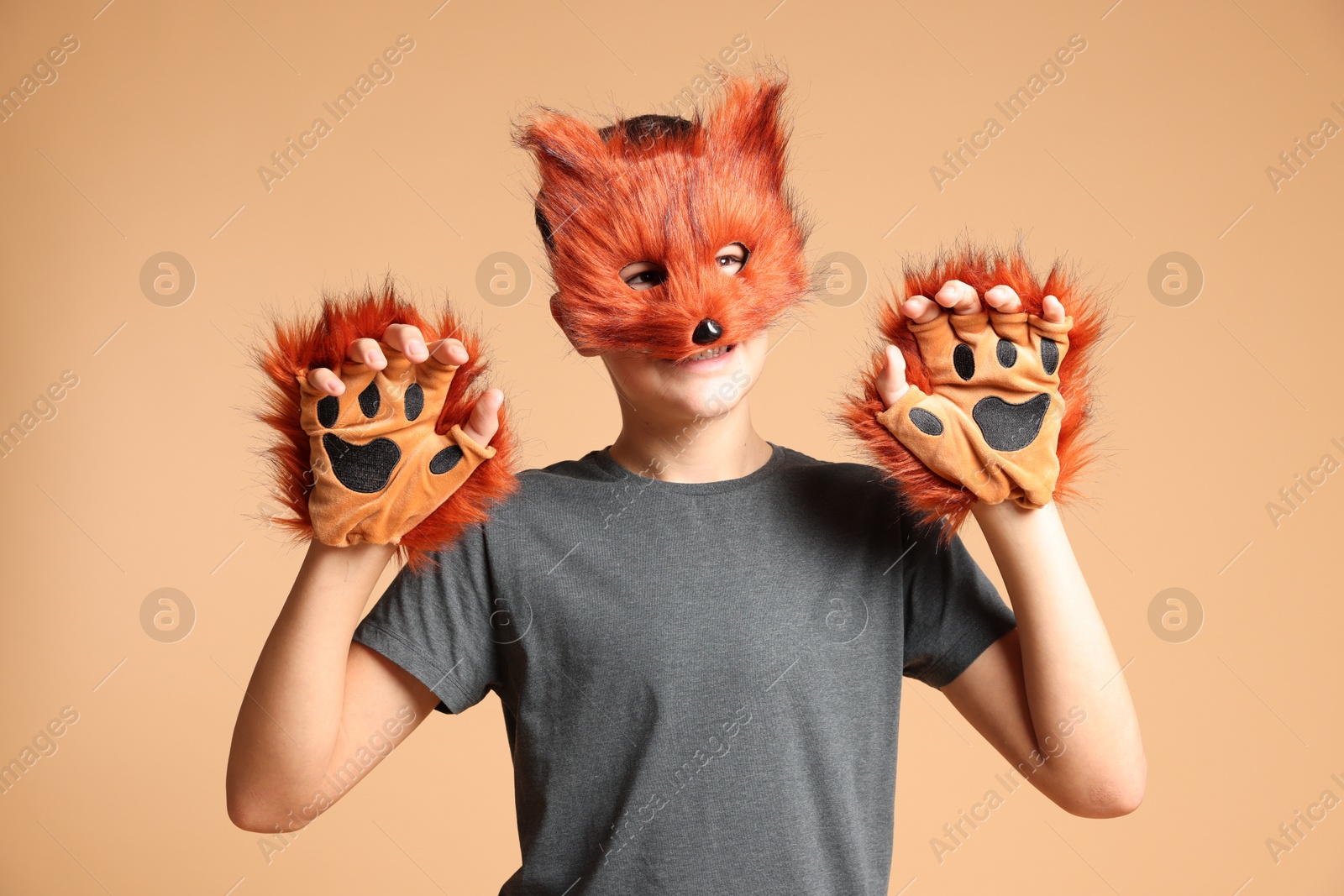 Photo of Quadrobics. Boy wearing fox mask and gloves on beige background