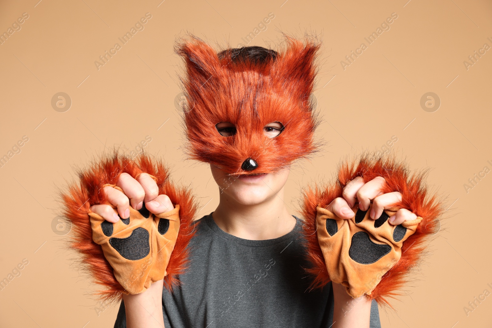 Photo of Quadrobics. Boy wearing fox mask and gloves on beige background