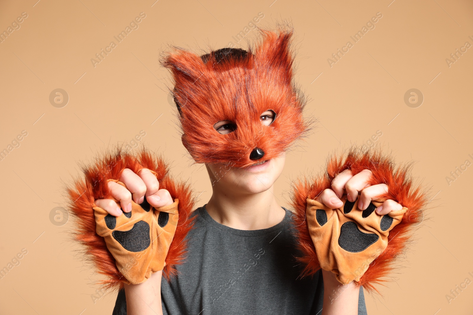 Photo of Quadrobics. Boy wearing fox mask and gloves on beige background