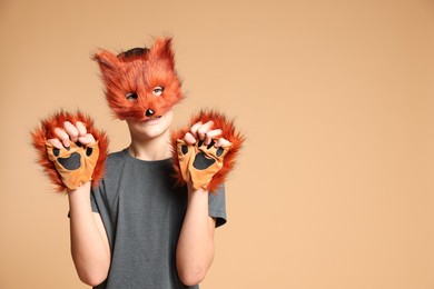 Photo of Quadrobics. Boy wearing fox mask and gloves on beige background, space for text