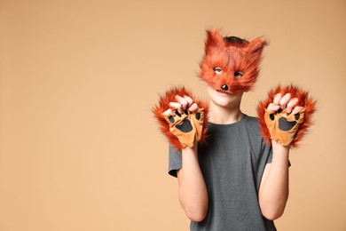 Quadrobics. Boy wearing fox mask and gloves on beige background, space for text