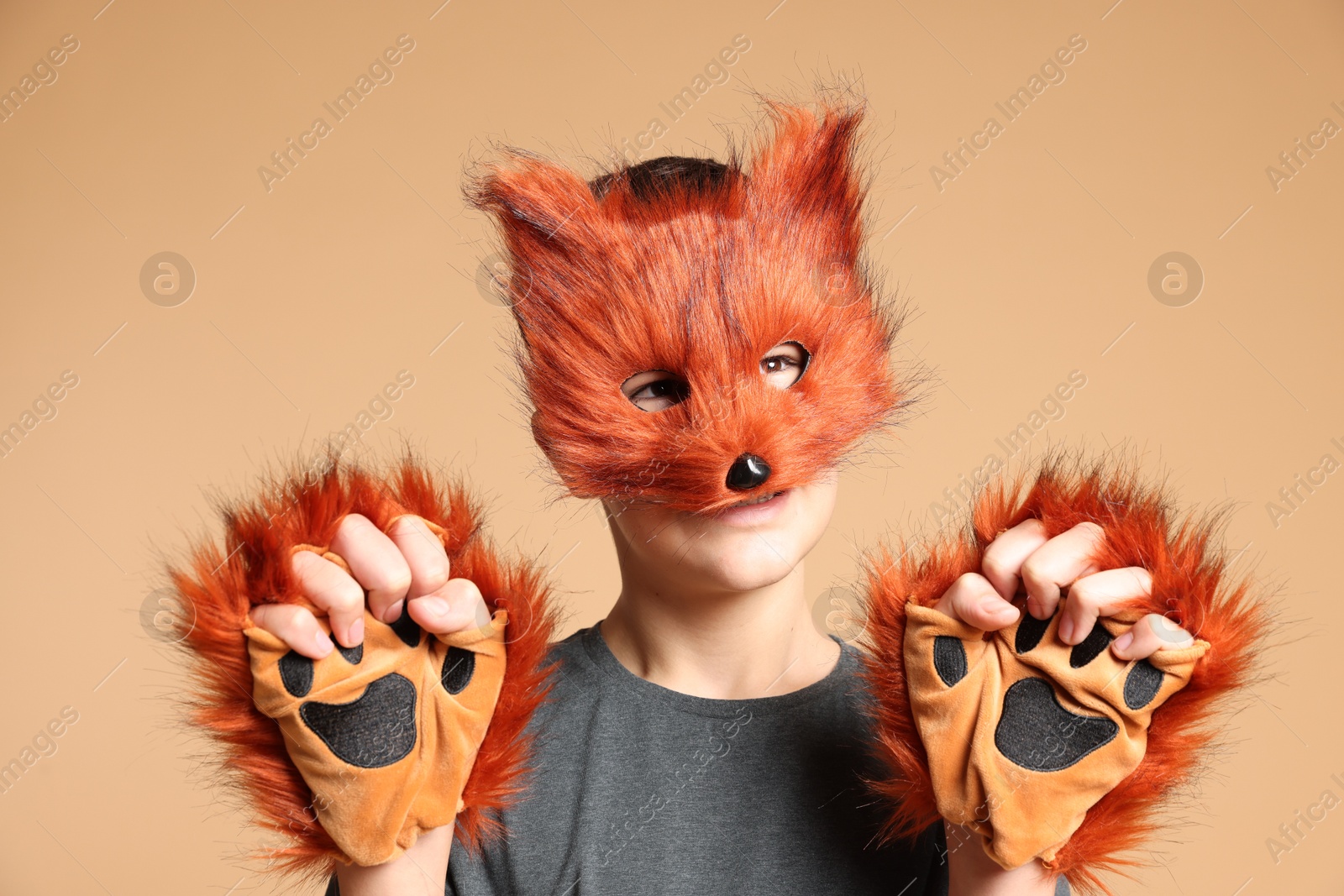 Photo of Quadrobics. Boy wearing fox mask and gloves on beige background