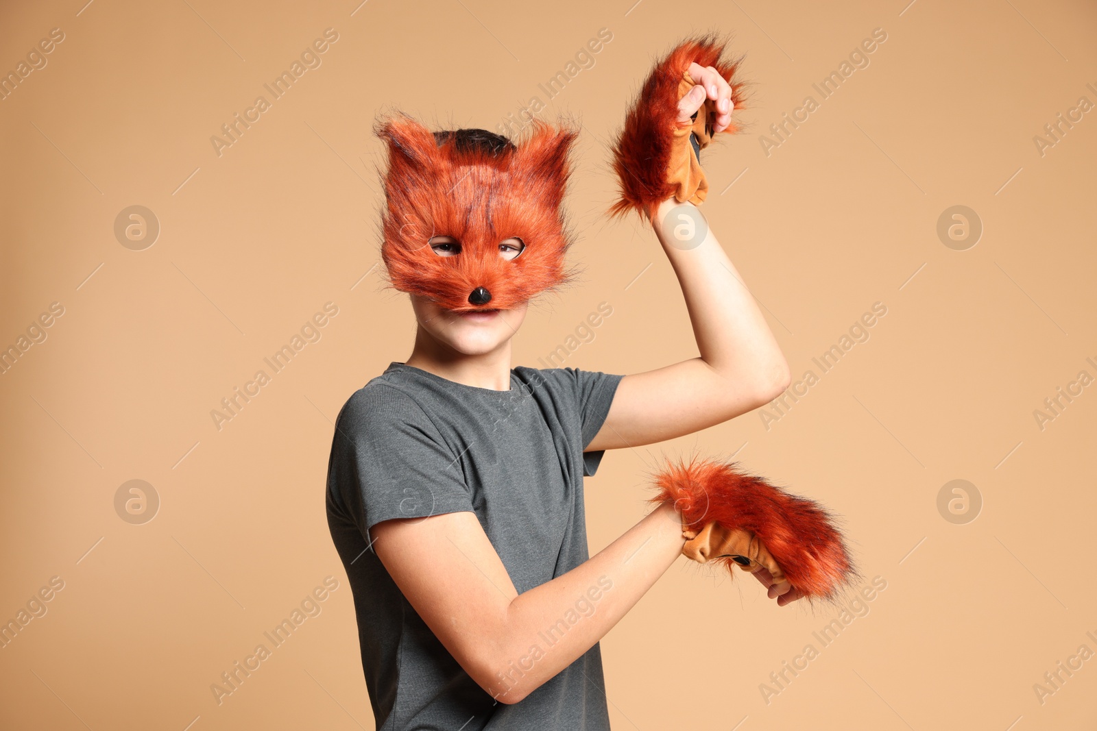 Photo of Quadrobics. Boy wearing fox mask and gloves on beige background