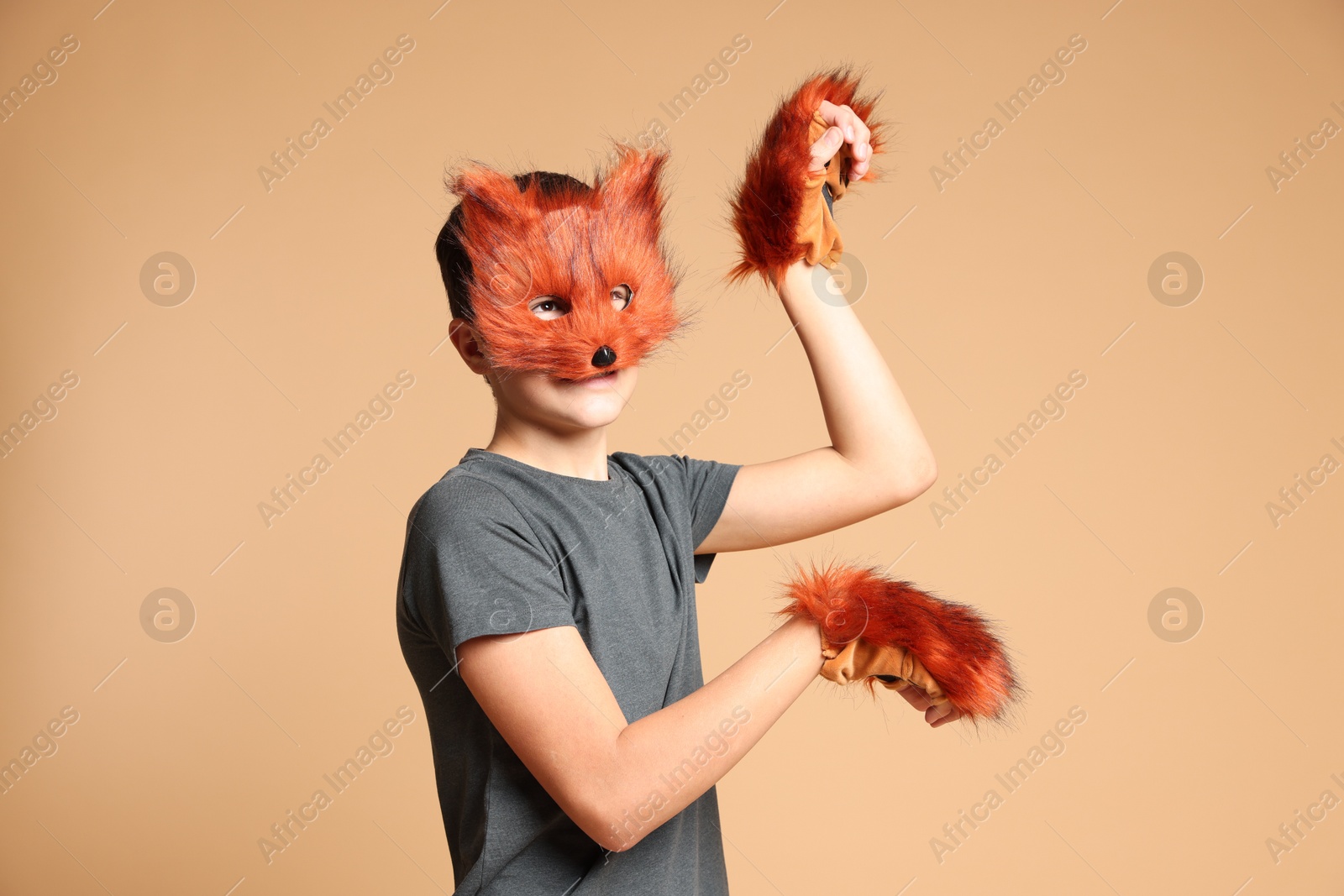 Photo of Quadrobics. Boy wearing fox mask and gloves on beige background