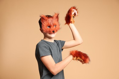 Photo of Quadrobics. Boy wearing fox mask and gloves on beige background