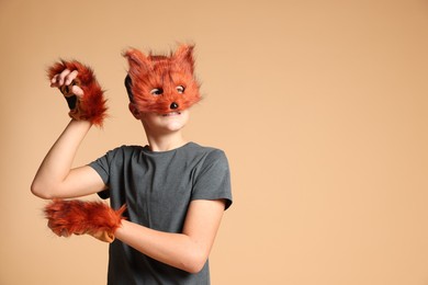 Quadrobics. Boy wearing fox mask and gloves on beige background, space for text