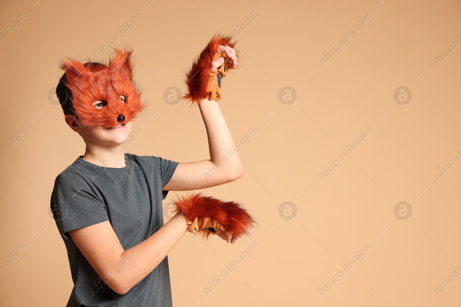 Photo of Quadrobics. Boy wearing fox mask and gloves on beige background, space for text