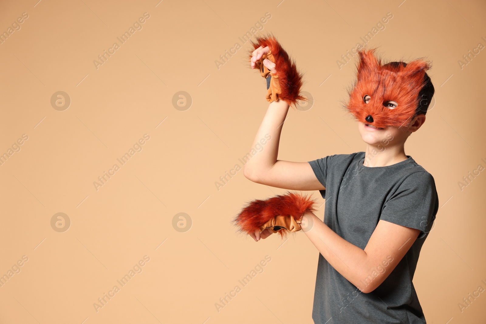 Photo of Quadrobics. Boy wearing fox mask and gloves on beige background, space for text