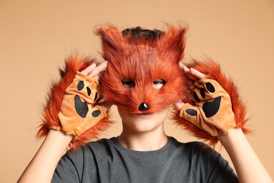 Quadrobics. Boy wearing fox mask and gloves on beige background