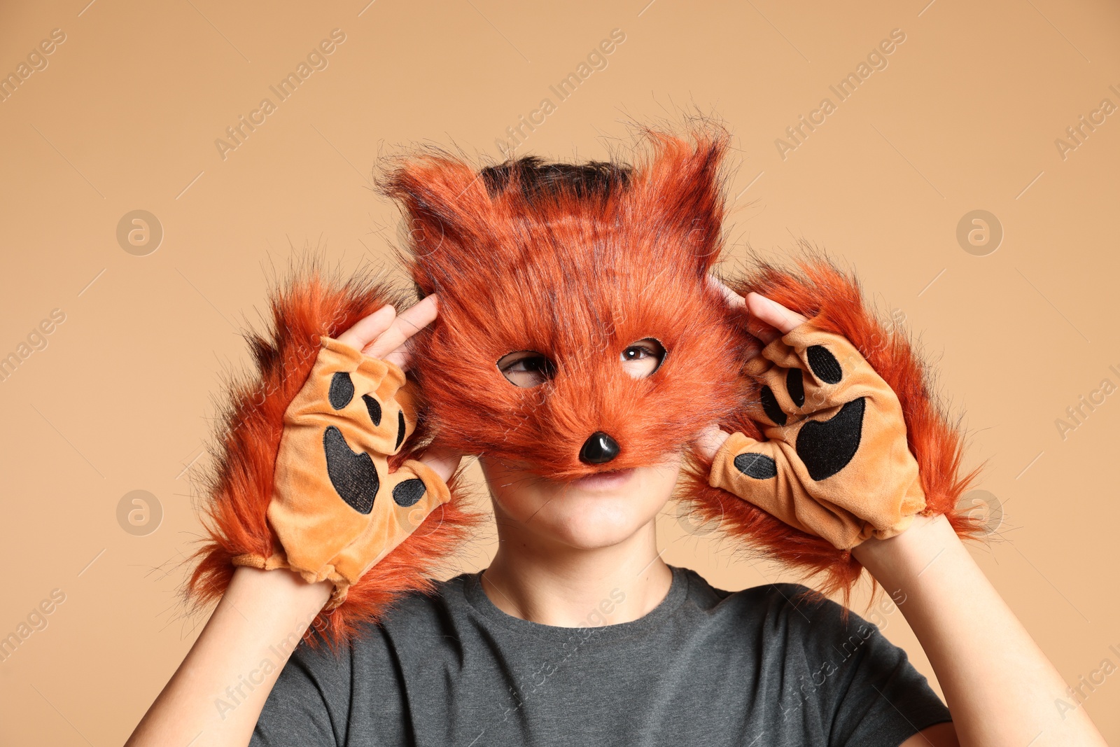 Photo of Quadrobics. Boy wearing fox mask and gloves on beige background