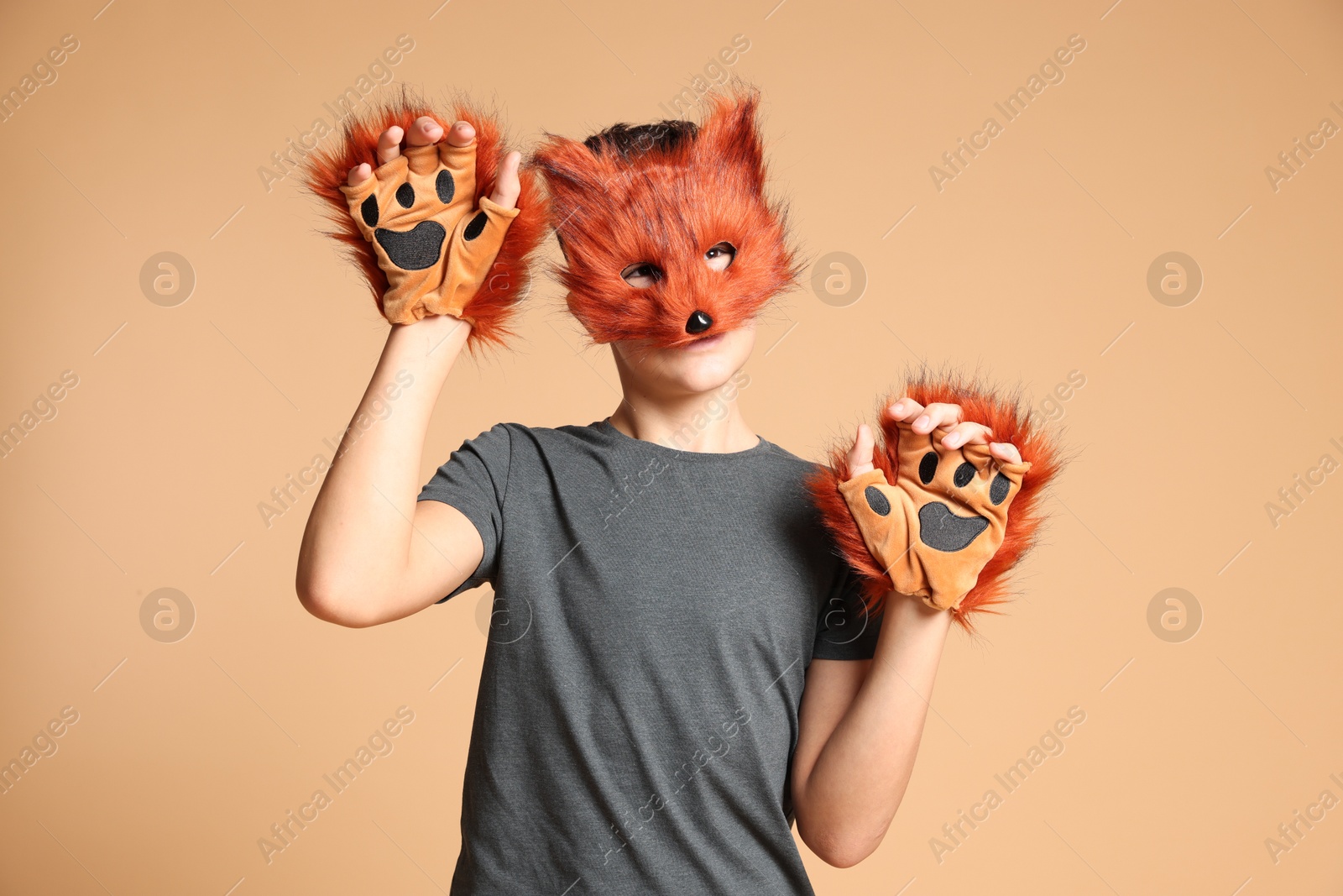 Photo of Quadrobics. Boy wearing fox mask and gloves on beige background