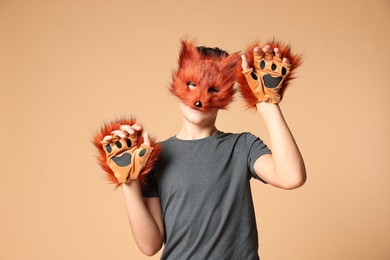 Quadrobics. Boy wearing fox mask and gloves on beige background