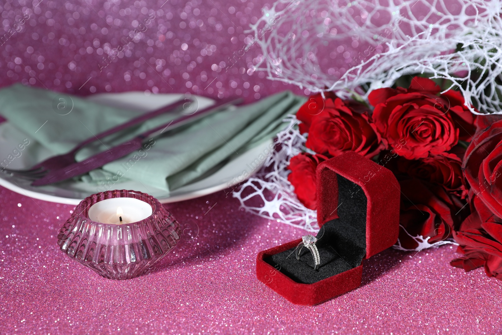 Photo of Beautiful setting for romantic dinner, engagement ring and roses on pink background