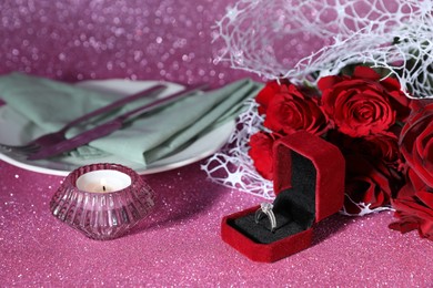 Photo of Beautiful setting for romantic dinner, engagement ring and roses on pink background