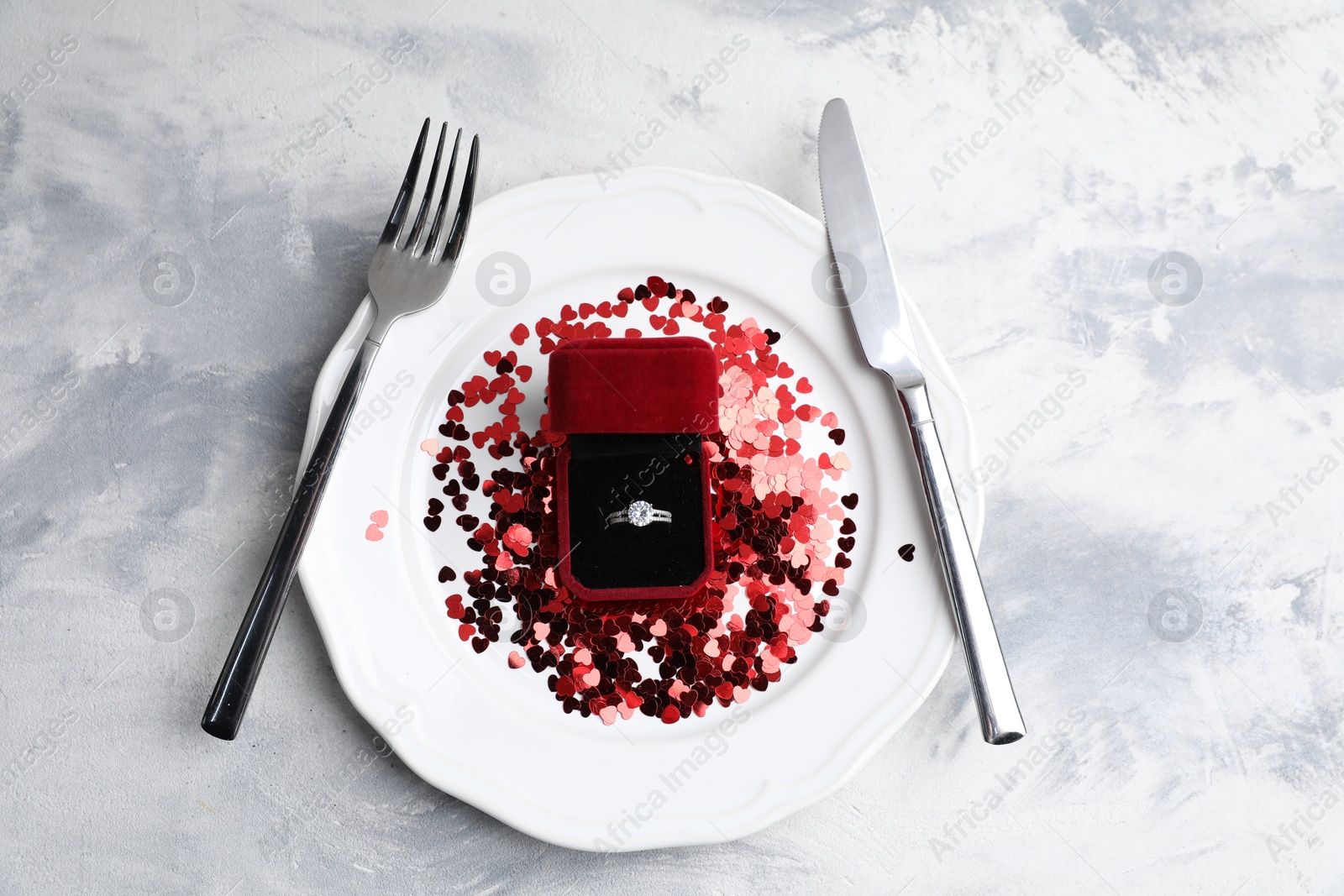 Photo of Beautiful setting for romantic dinner and engagement ring on color textured table, top view